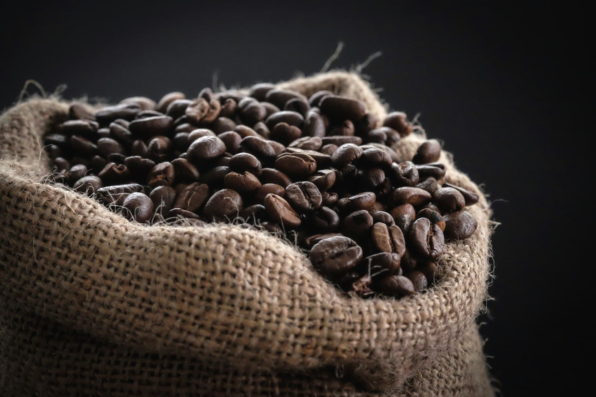 Roasted coffee beans spilling from a jute sack